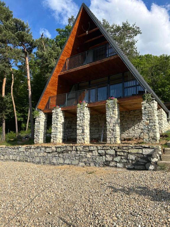 a house with a stone wall and a roof at Cabana Icas in Dej