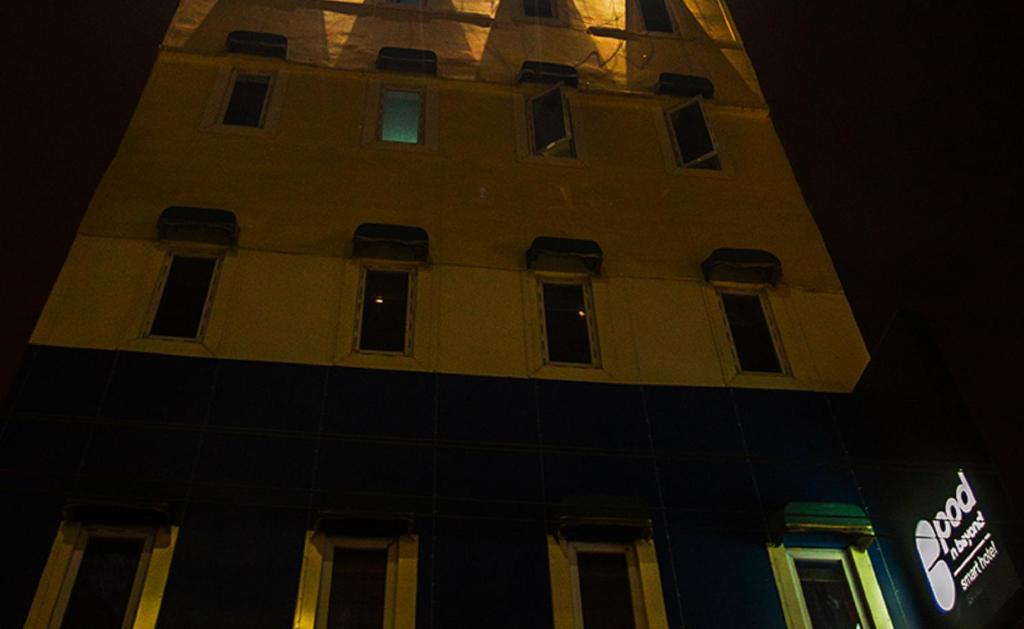 un grand bâtiment avec une tour d'horloge la nuit dans l'établissement Pod N Beyond Smart Hotel, à Jamshedpur
