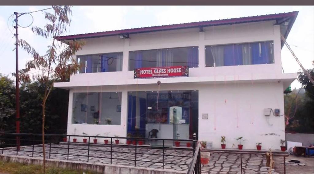 a white building with a sign that reads music cafe house at Hotel glass house in Kāta Patthar