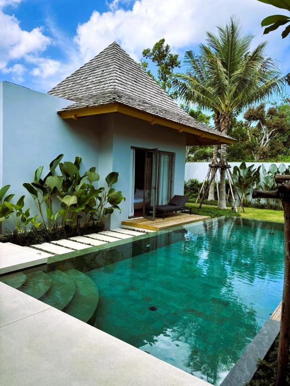 a villa with a swimming pool in front of a house at Lucky Eight Villa in Ban Phru Champa