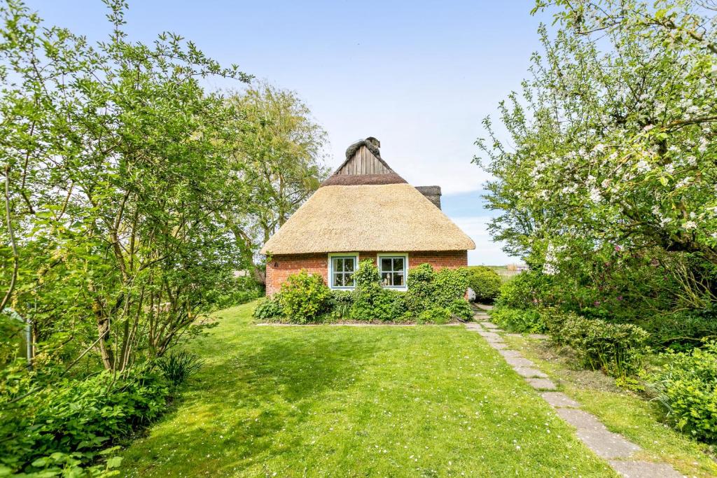 an old house with a thatched roof in a garden at Achtern Diek in Schülp