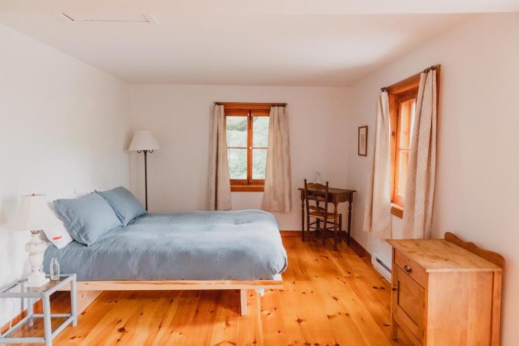 a bedroom with a bed and a wooden floor at Triangle de l'Île Chambre Belle Bleue in Saint-Laurent-de-l'ile d'Orleans