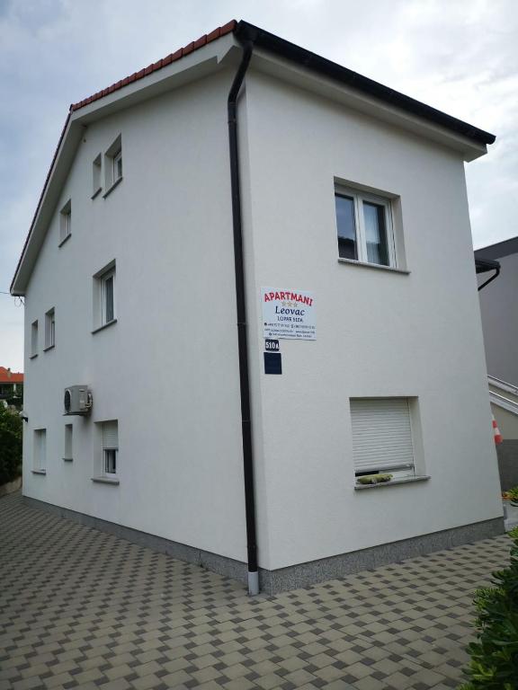 a large white building with windows on the side at Apartmani Leovac in Lopar