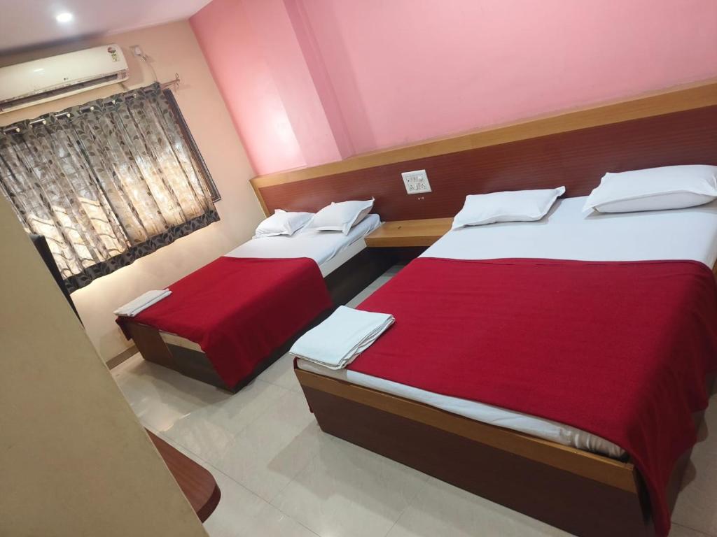 two beds in a small room with red sheets at Hotel SS Palace in Shirdi