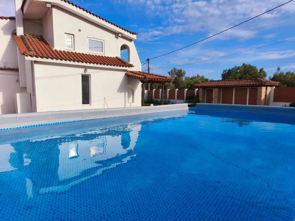 a villa with a swimming pool in front of a house at Villa Oneiron in Anavyssos