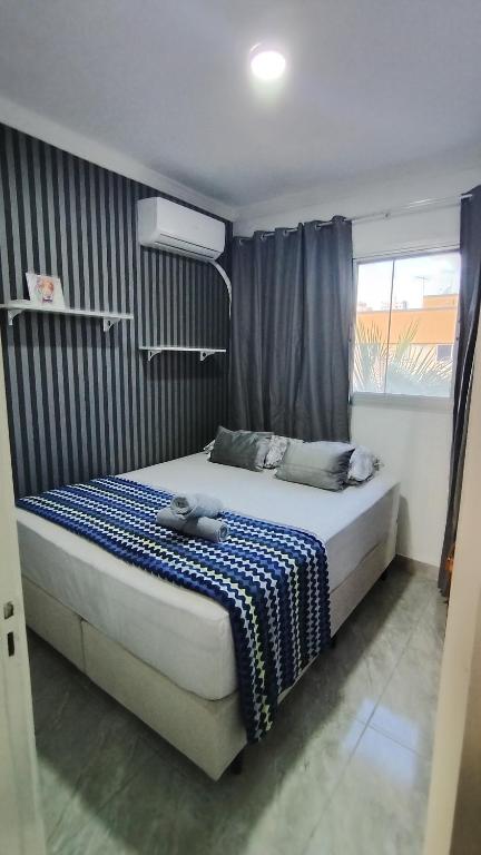 a bedroom with a bed with a blue and white blanket at Dois quartos mobiliado próximo a praia in Vila Velha