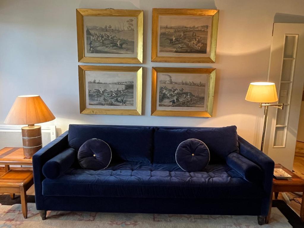 a blue couch in a living room with pictures on the wall at le Pullman in Deauville