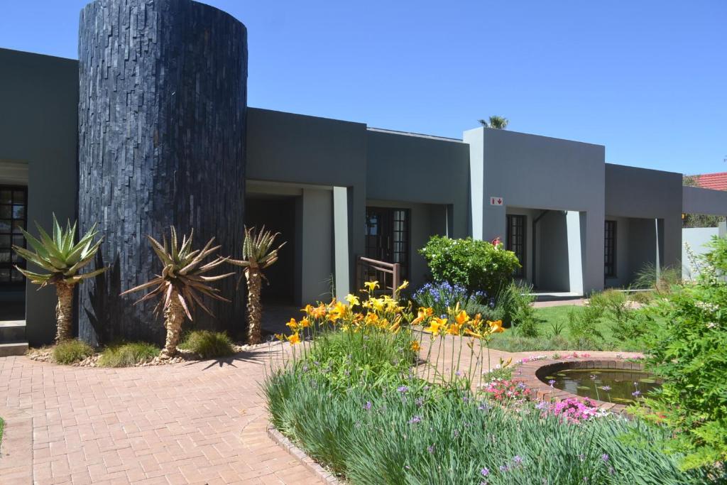 a building with a garden with flowers in front of it at Be At Home Guesthouse in Klerksdorp