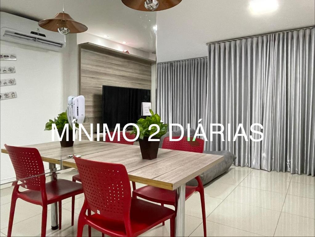 a dining room with a wooden table and red chairs at Lounge 22 barato 12e13agosto in Goiânia