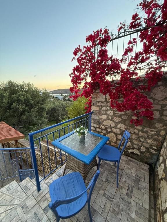 a blue table and chairs on a balcony with flowers at Vila Katerina Qeparo in Qeparo