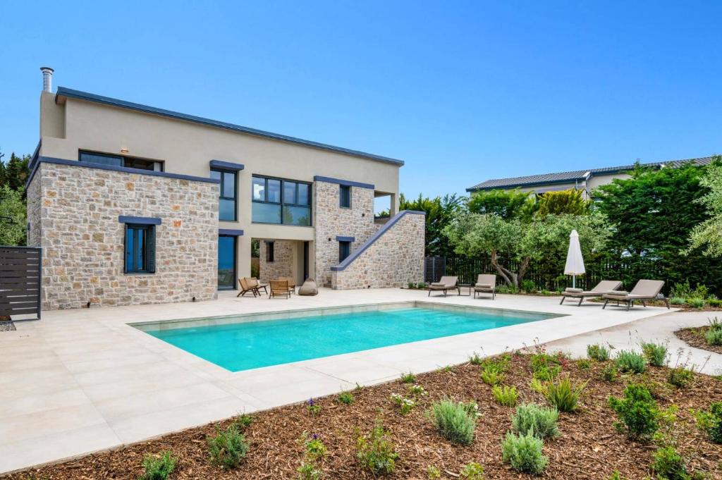 a swimming pool in front of a house at Villa Cypressa by Villa Plus in Kalamitsi