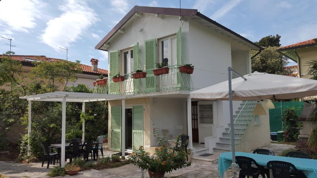 a house with green shutters and a table and an umbrella at Le Mura Holiday Home in Marina di Pietrasanta