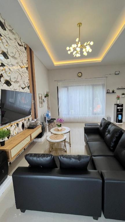 a living room with a black couch and a table at Villa Adela Sky Land Malang in Karangploso