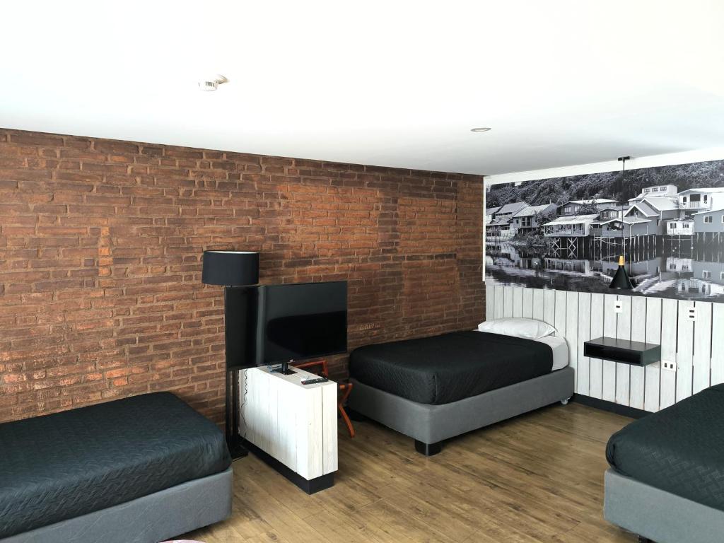 a bedroom with two beds and a brick wall at Hostal Boutique Black Cat in Santiago