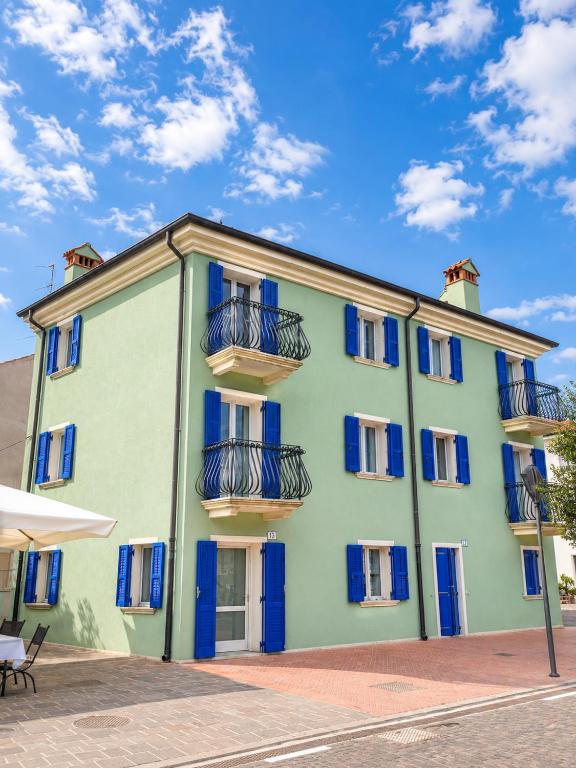 a green building with blue windows and balconies at Casa del Marinaio - Agenzia Cocal in Caorle