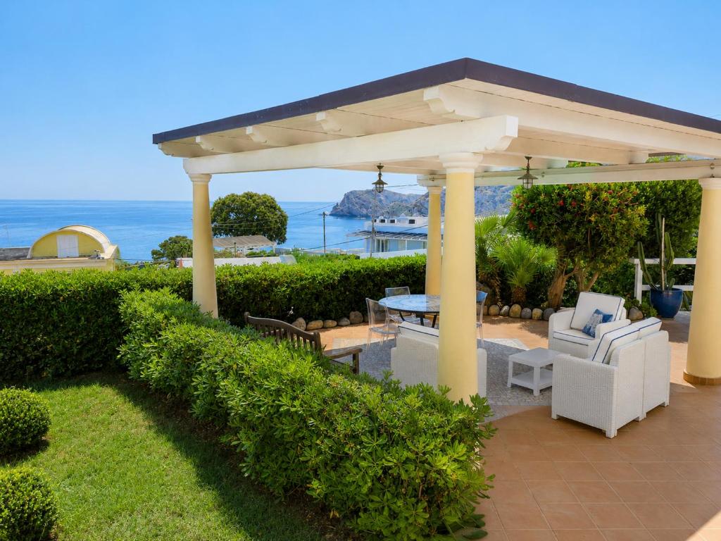 a pavilion with a table and chairs and the ocean at Maridea - Villetta Brezza Marina in Ponza