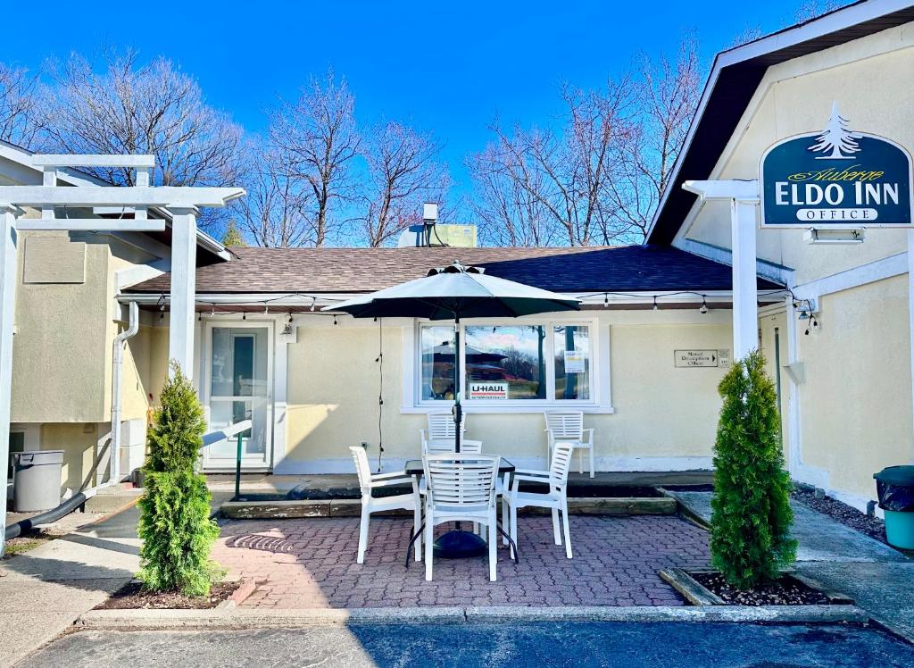 a patio with a table and chairs and an umbrella at Auberge Eldo Inn in Blind River