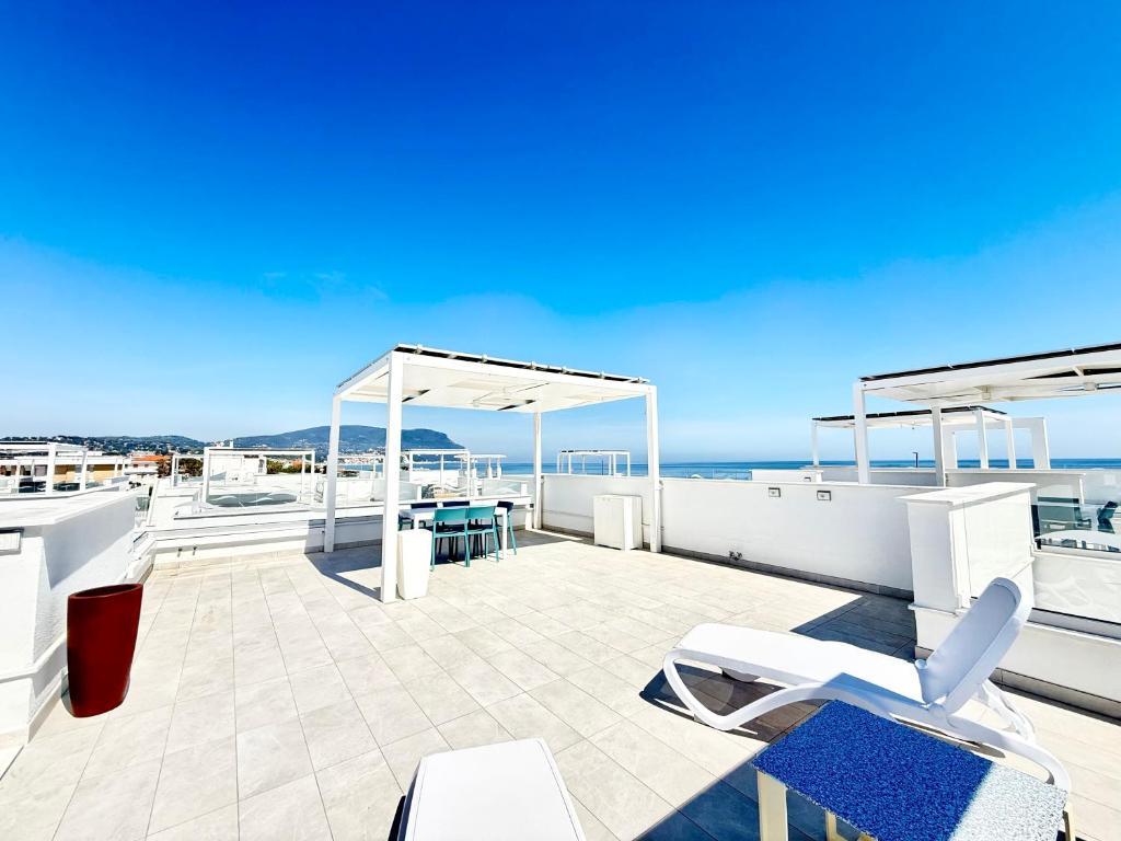 a patio with white chairs and tables on a roof at Conero View in Marcelli