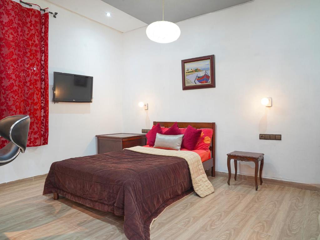 a bedroom with a bed with red pillows and a tv at Agréable suite situé dans une villa in Rabat