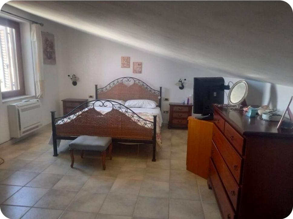 a bedroom with a bed and a dresser and a television at Casa Wendy in Carloforte