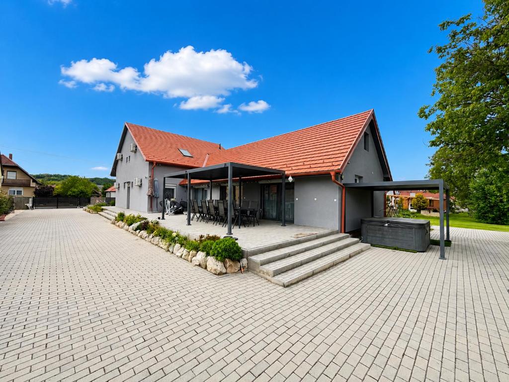 a house with a red roof on a brick driveway at Ulics vendégház II in Zalacsány
