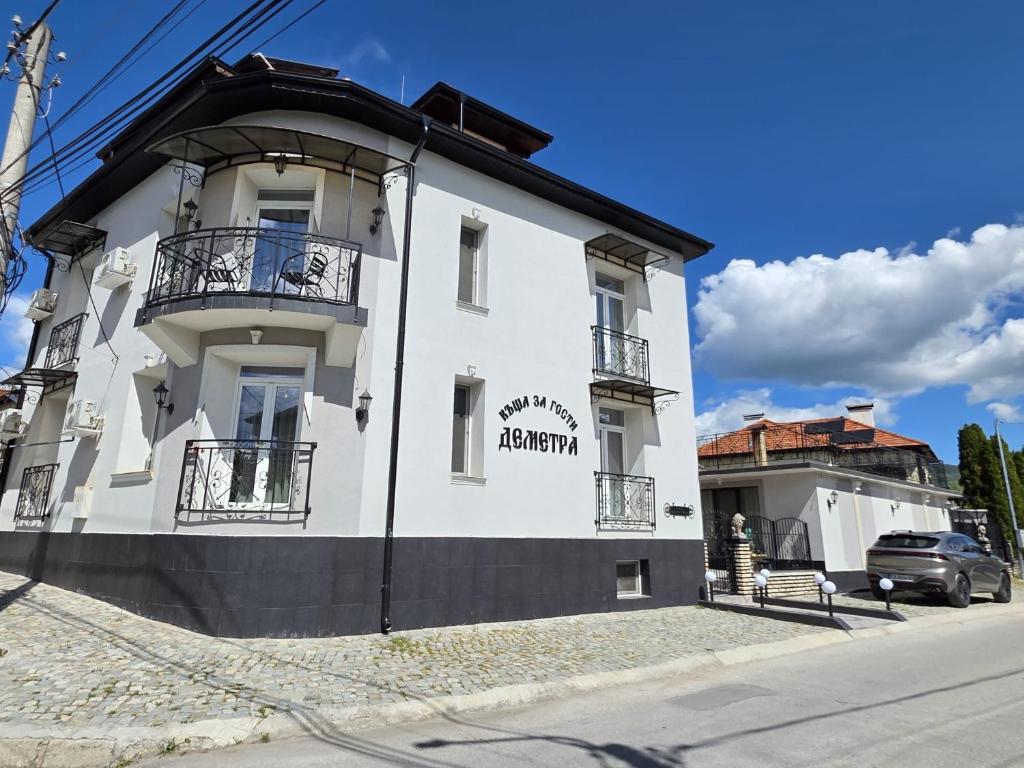 a white building on the side of a street at Къща за гости Деметра in Velingrad