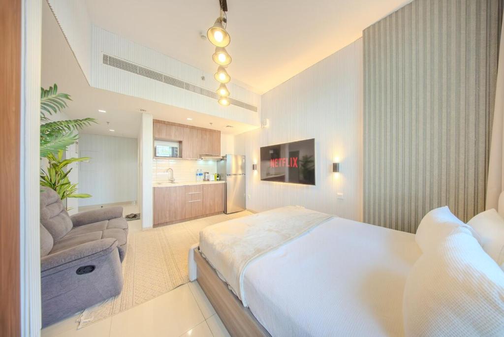 a bedroom with a large white bed and a couch at Luxury Studio With Private Garden - Uptown Al Zahia Sharjah in Ḩiz̧āyib az Zānah