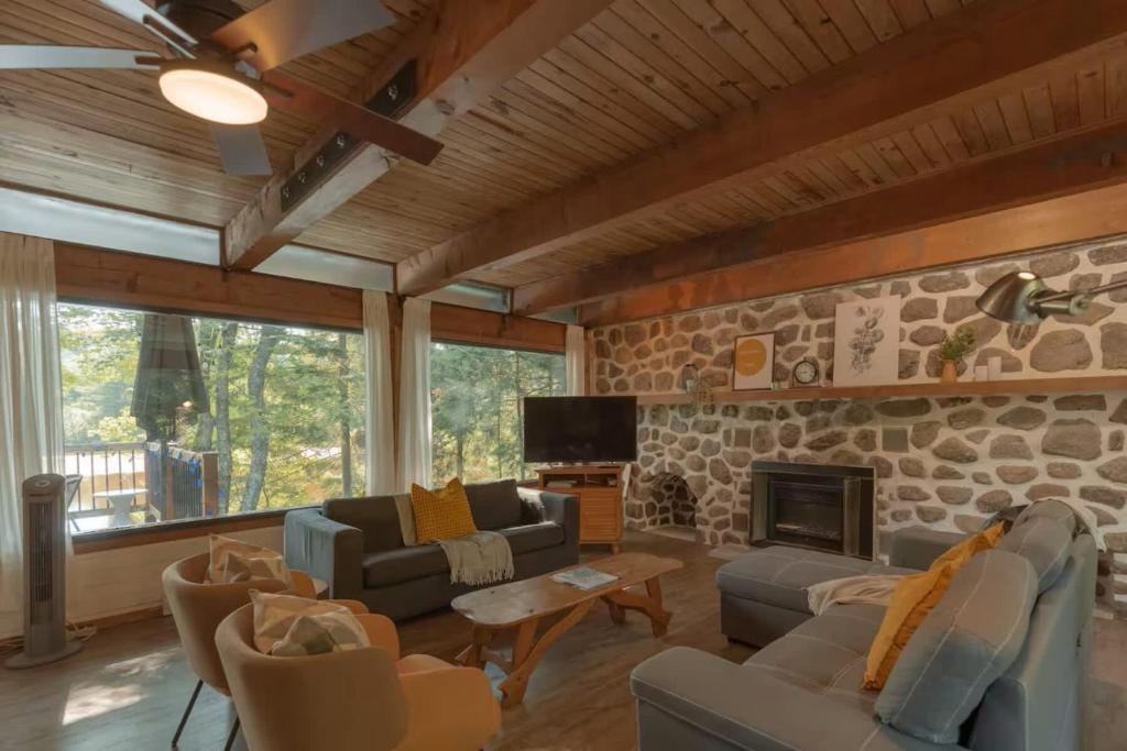 a living room with a stone wall at Riverfront Getaway with Hot Tub and Scenic Views in Mont-Tremblant