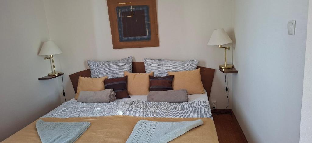 a bed with many pillows on it in a room at Andante apartman in Bük