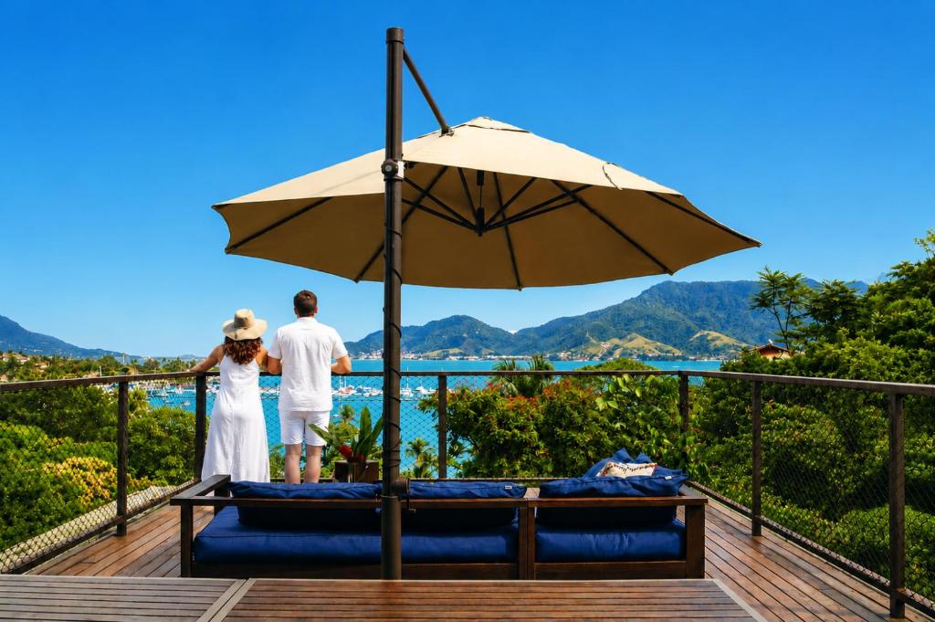 a bride and groom standing on a deck under an umbrella at Vila Bambu Ilhabela, Santa Tereza in Ilhabela