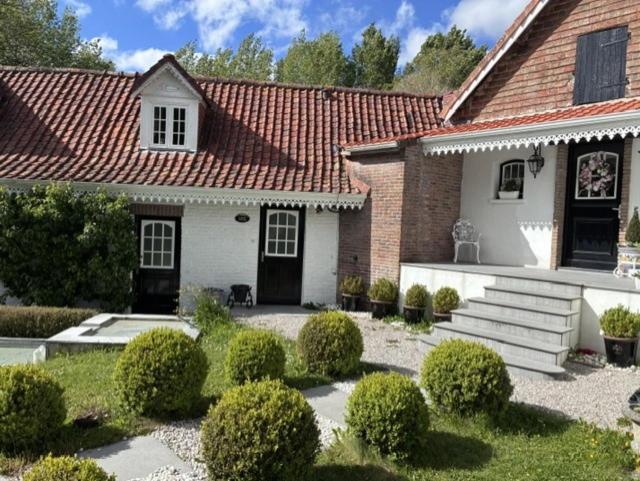 a white house with a red roof and some bushes at Les 4 saisons in Menneville