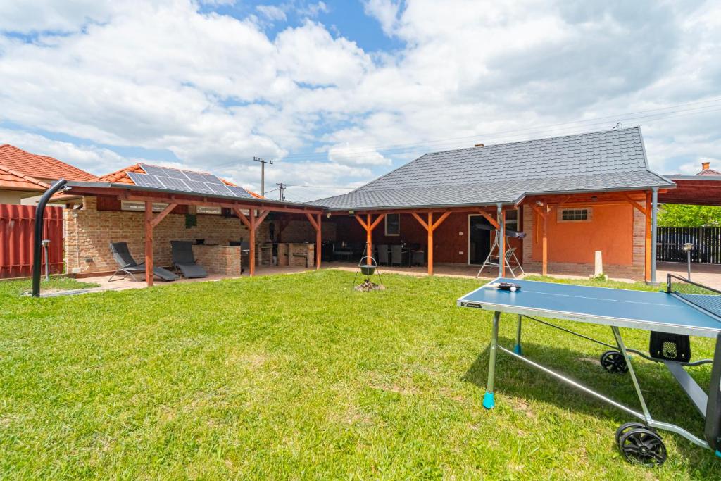 a ping pong table in a yard in front of a house at Indok Vendégház in Abádszalók
