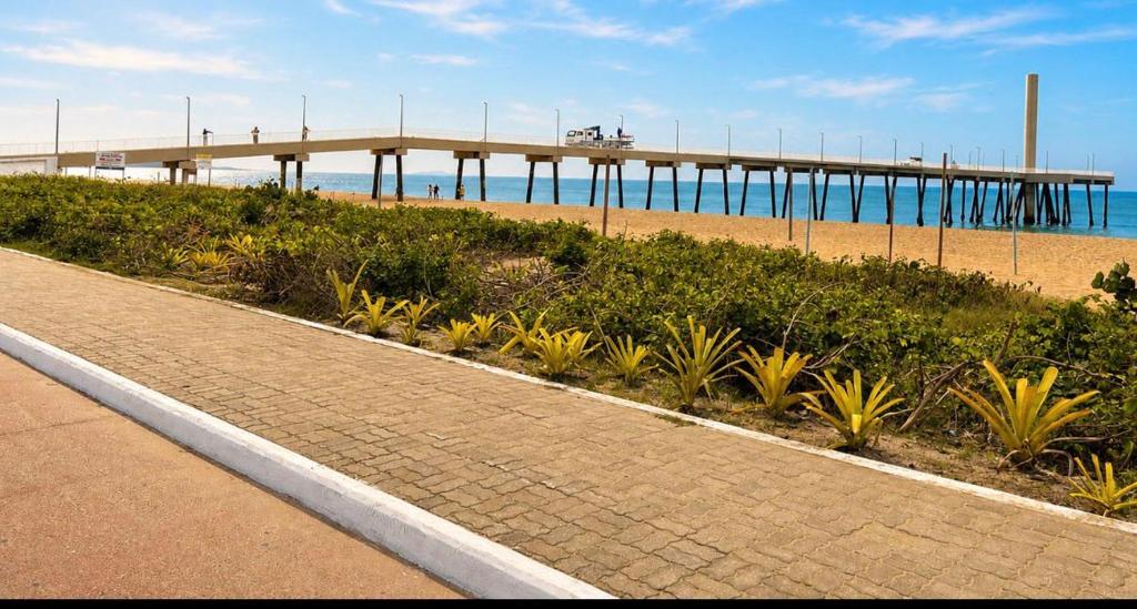 a sidewalk next to a beach with a pier at Casa da Dinda 203 in Rio das Ostras