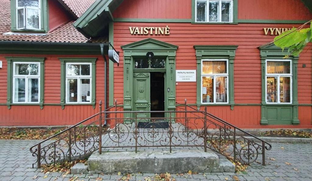 a red building with a gate in front of a door at Ambra Apartaments Palanga in Palanga