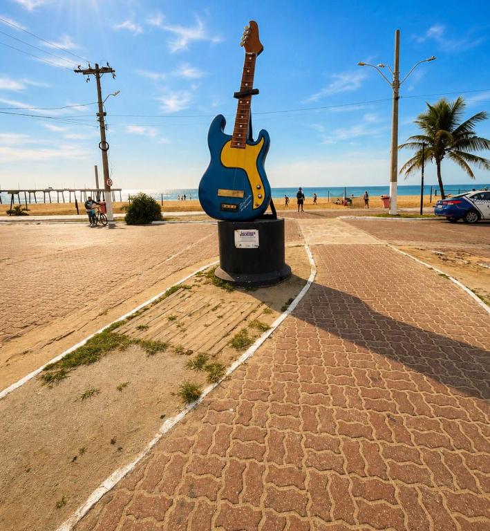 a statue of a guitar on the beach at Casa da Dinda 104 in Rio das Ostras