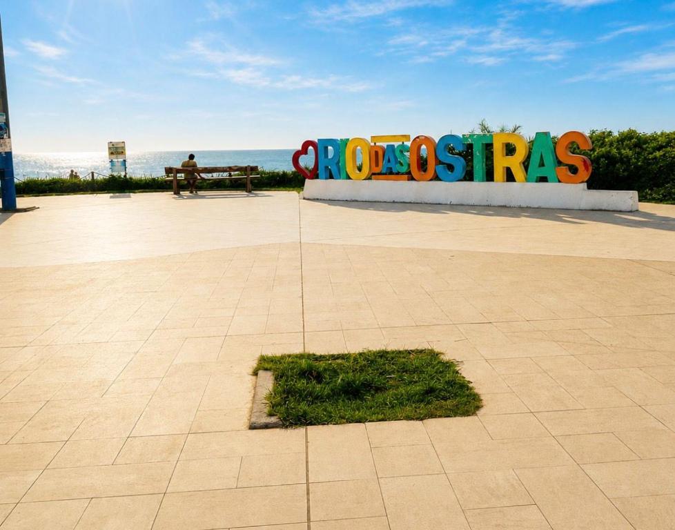 a person sitting on a bench in front of a sign at Casa da Dinda 202 in Rio das Ostras