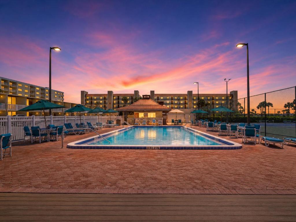 a large swimming pool with chairs and a building at Ocean Landings Resort Cocoa Beach Port Canaveral in Cocoa Beach