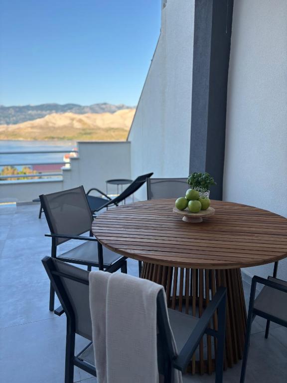 a wooden table and chairs with a bowl of fruit on it at Modern Panoramic Sea View Apartment with Large Terrace in Pag
