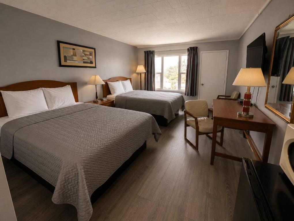 a hotel room with two beds and a desk at Belmont Inn in Sudbury