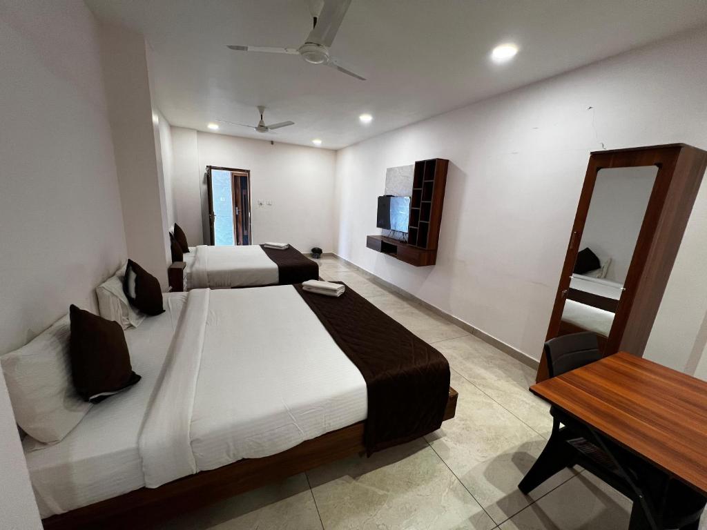 a hotel room with two beds and a mirror at Hotel Church Way Inn in Velankanni