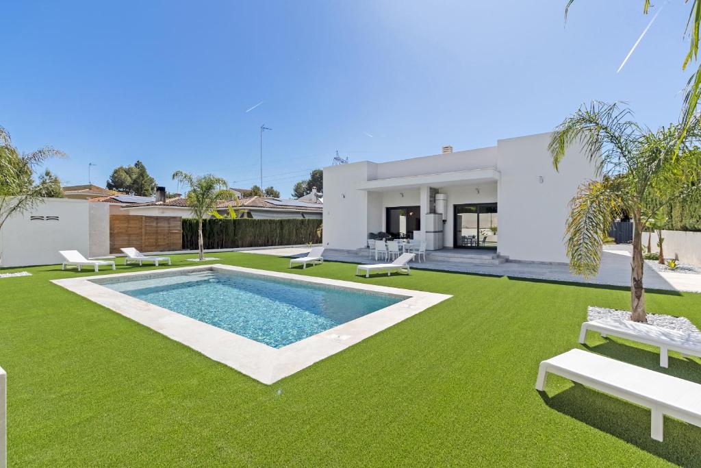 a backyard with a swimming pool and green grass at Oasis los Lagos in Alginet