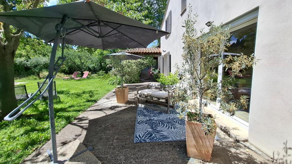 an umbrella and a bench next to a house at Ginette et Marcel la maison in Saint-Rémy-de-Provence