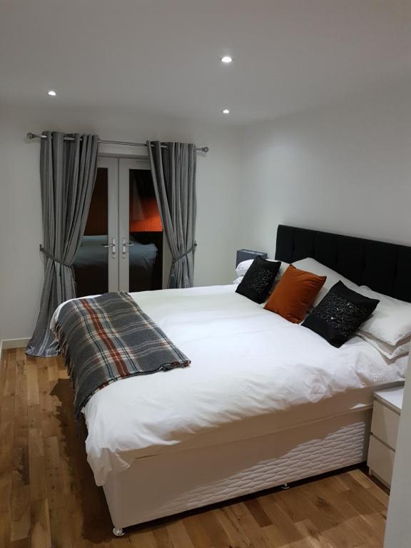 a bedroom with a bed with white sheets and orange pillows at LANGLEY APARTMENT free parking outside between 6 pm and 8 am Secure parking 2 min walk Ideal for TRADES AND TOURISTS WANTING GREAT LOCATION in Inverness