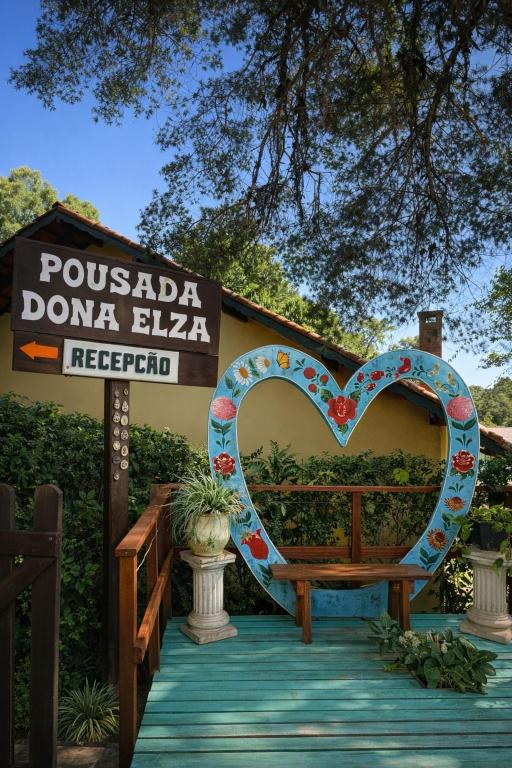 a heart shaped bench sitting in front of a sign at Pousada Dona Elza in Monte Verde