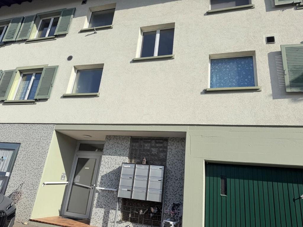 a building with a green door and a garage at Apartment in Reigoldswil in Reigoldswil