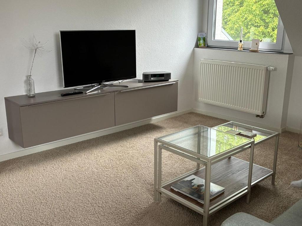 ein Wohnzimmer mit Flachbildfernseher und Glastisch in der Unterkunft Falltor Living in Rees