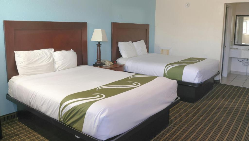 a hotel room with two beds with white and green sheets at Chippewa Motel Mount Pleasant in Mount Pleasant
