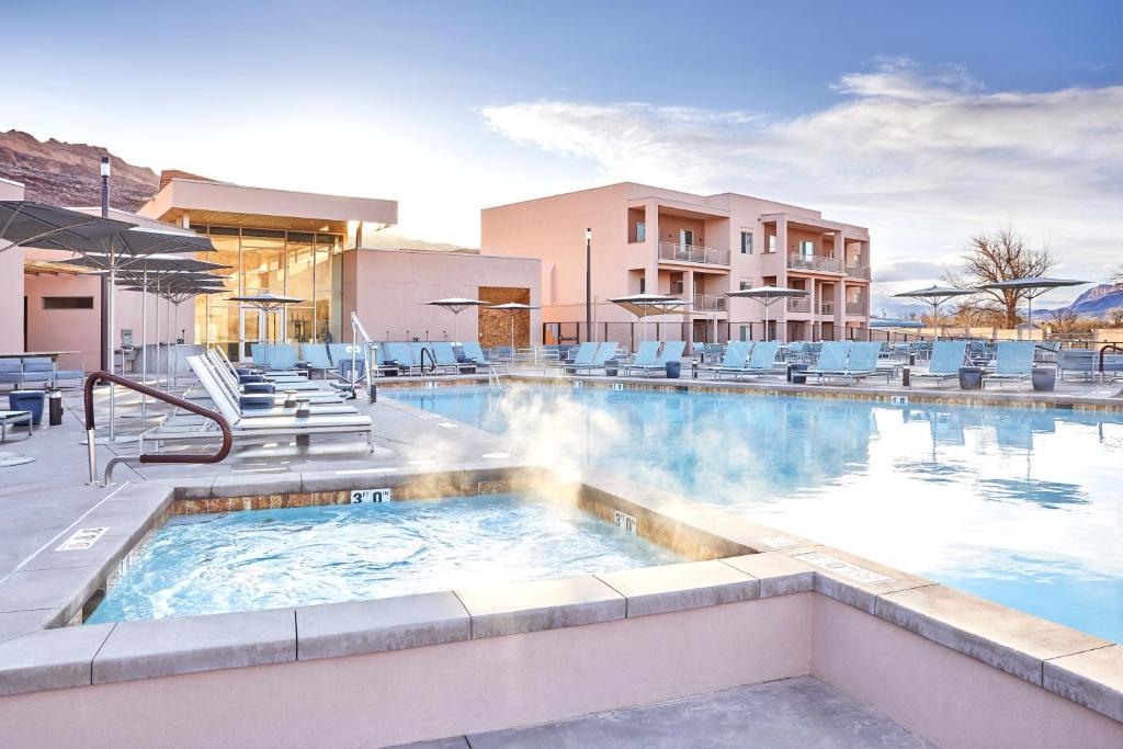a swimming pool with a hot tub and chairs at EBAC Moab in Moab
