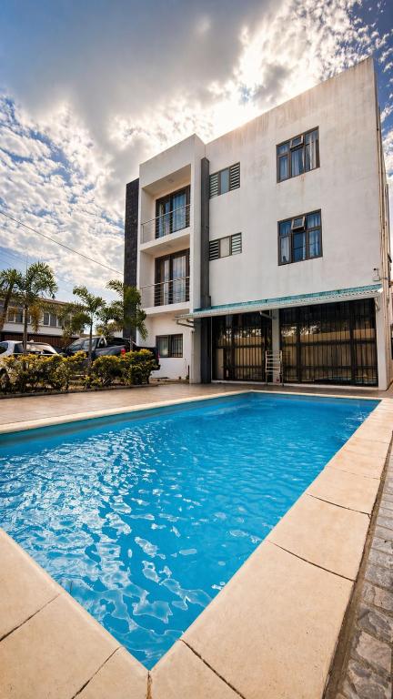 a building with a swimming pool in front of a building at Zenith Apartment in Baie du Tombeau