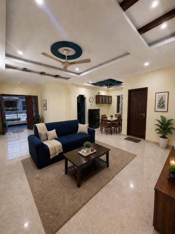 a living room with a blue couch and a table at Gachi Ghar Gachibowli 2 BHK in Hyderabad